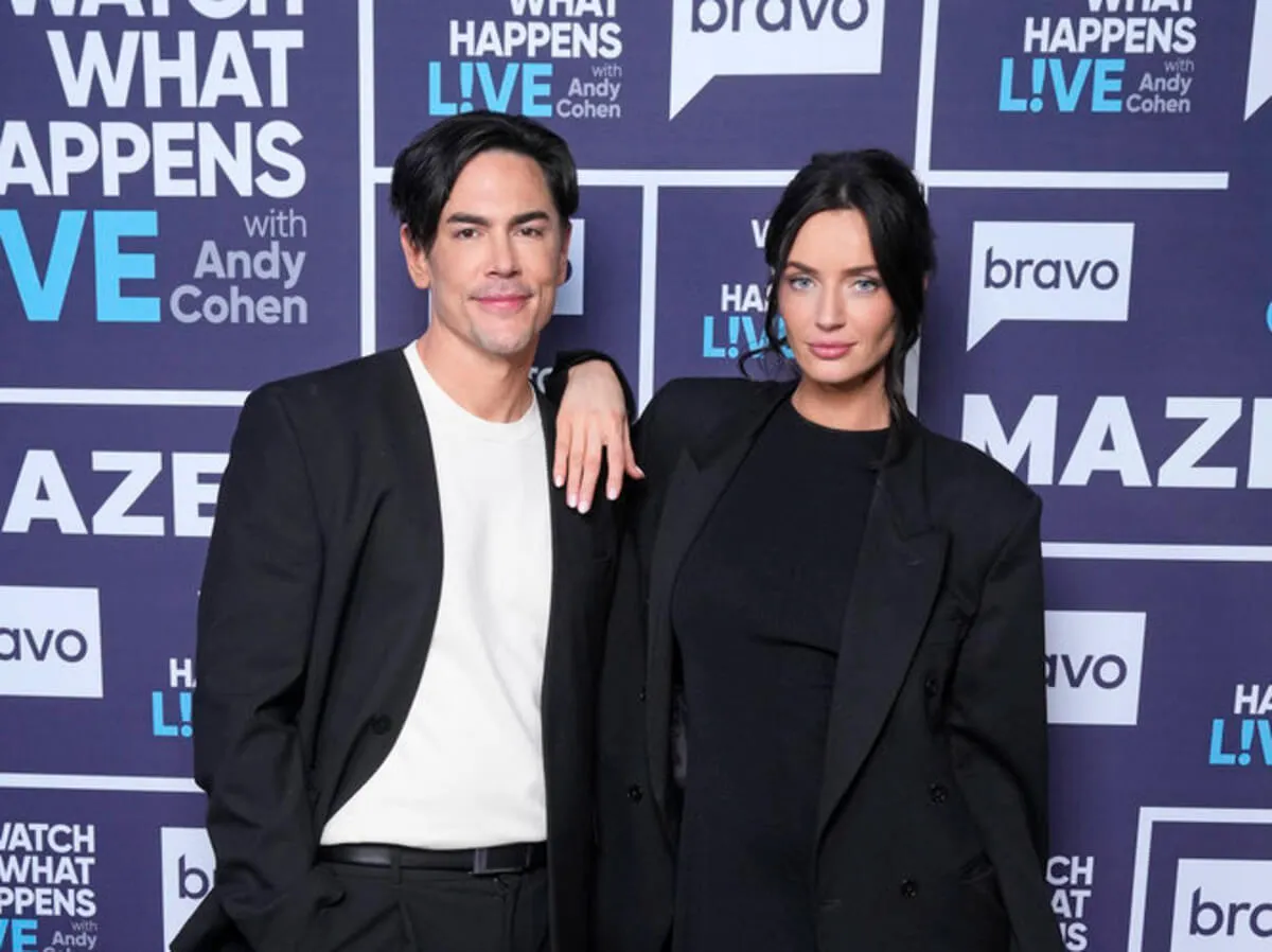 Tom Sandoval wears white with a black jacket. Victoria Lee Robinson wears black and rests her arm on his shoulder.