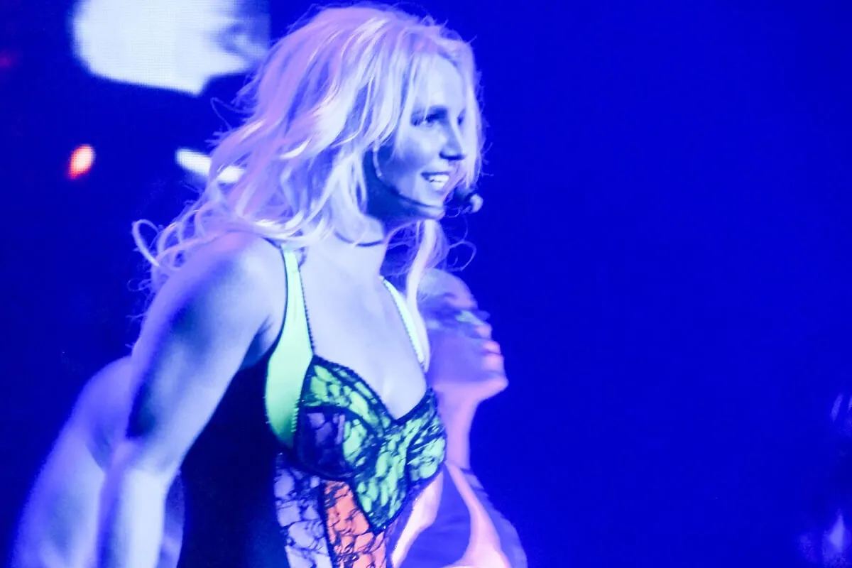 Britney Spears wears a colorful tank top and has a headset microphone.