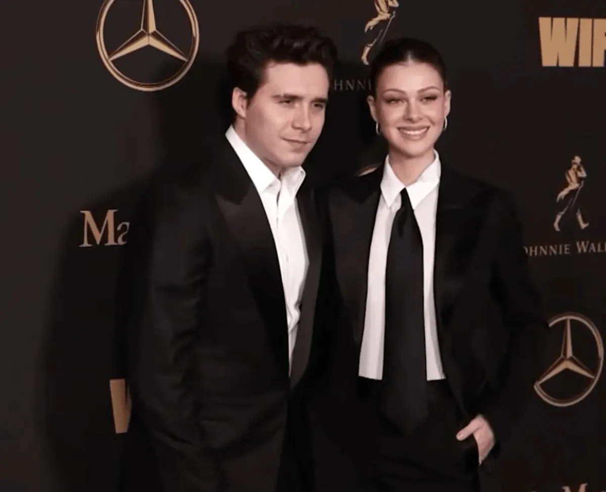Brooklyn Beckham and Nicola Peltz wear suits and stand together.