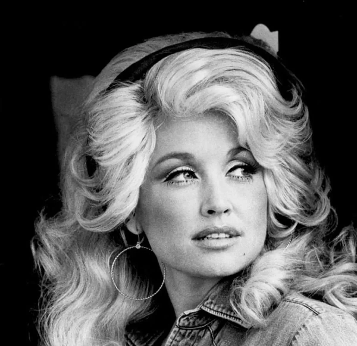 A black and white picture of Dolly Parton wearing a headband.