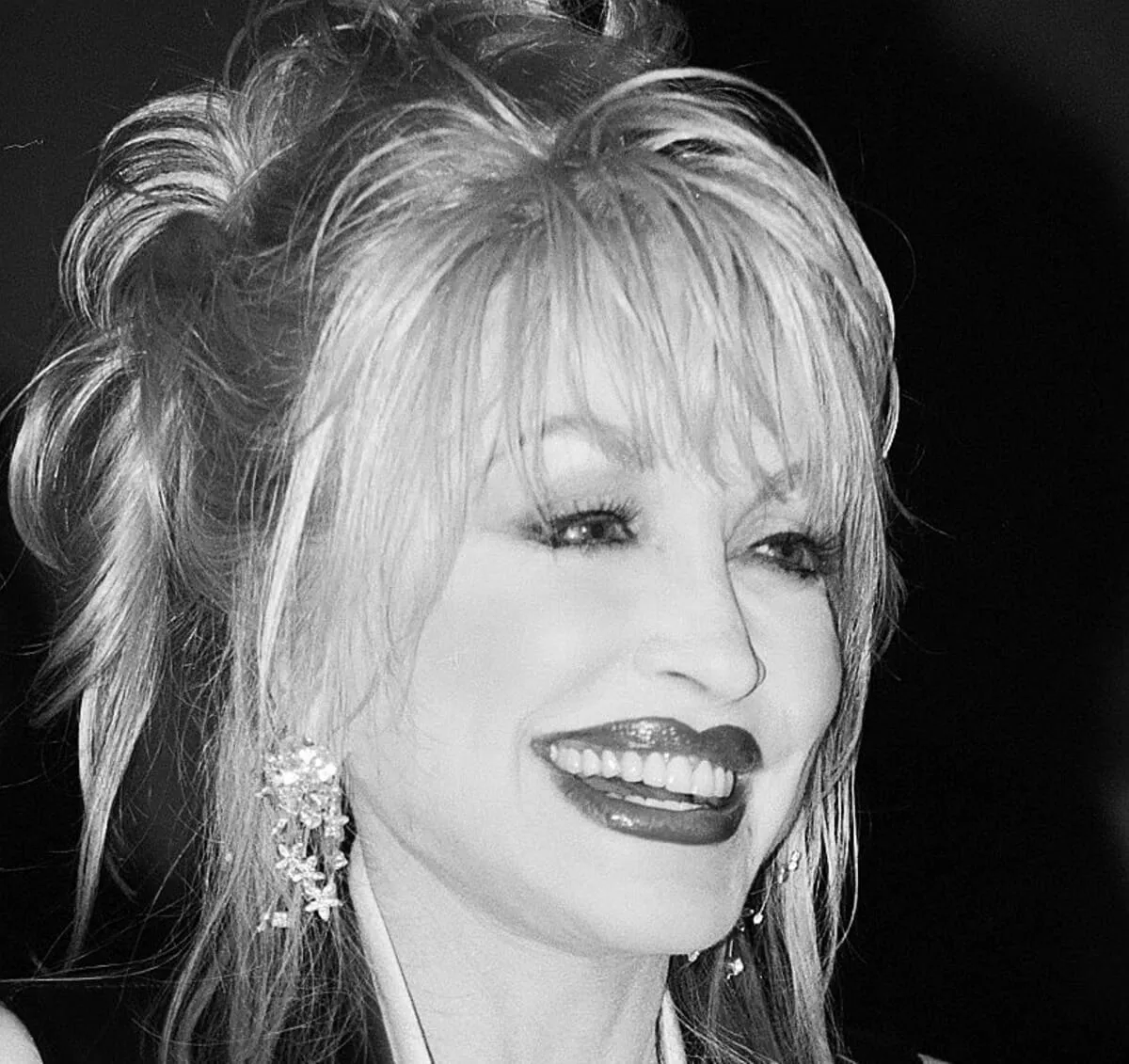 A black and white picture of Dolly Parton smiling.