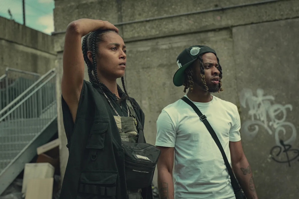 Jasmine Jobson as Jaq, with her arm over her head and standing next to Romy (Nyshai Caynes) in 'Top Boy' Season 5