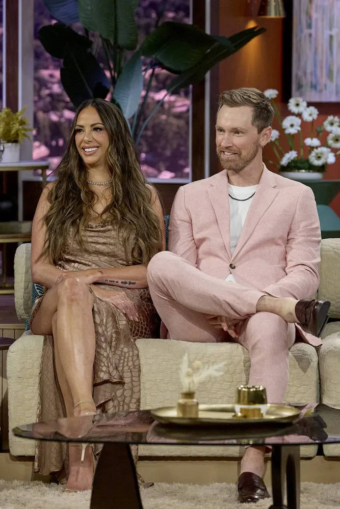 Kristen Doute sits next to Luke Broderick on a couch.
