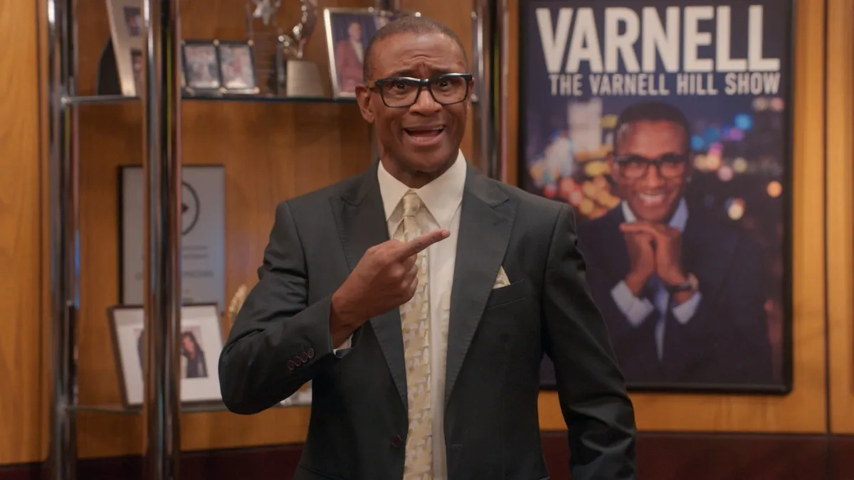 Tommy Davidson, wearing a suit and pointing at something, in 'The Varnell Hill Show'