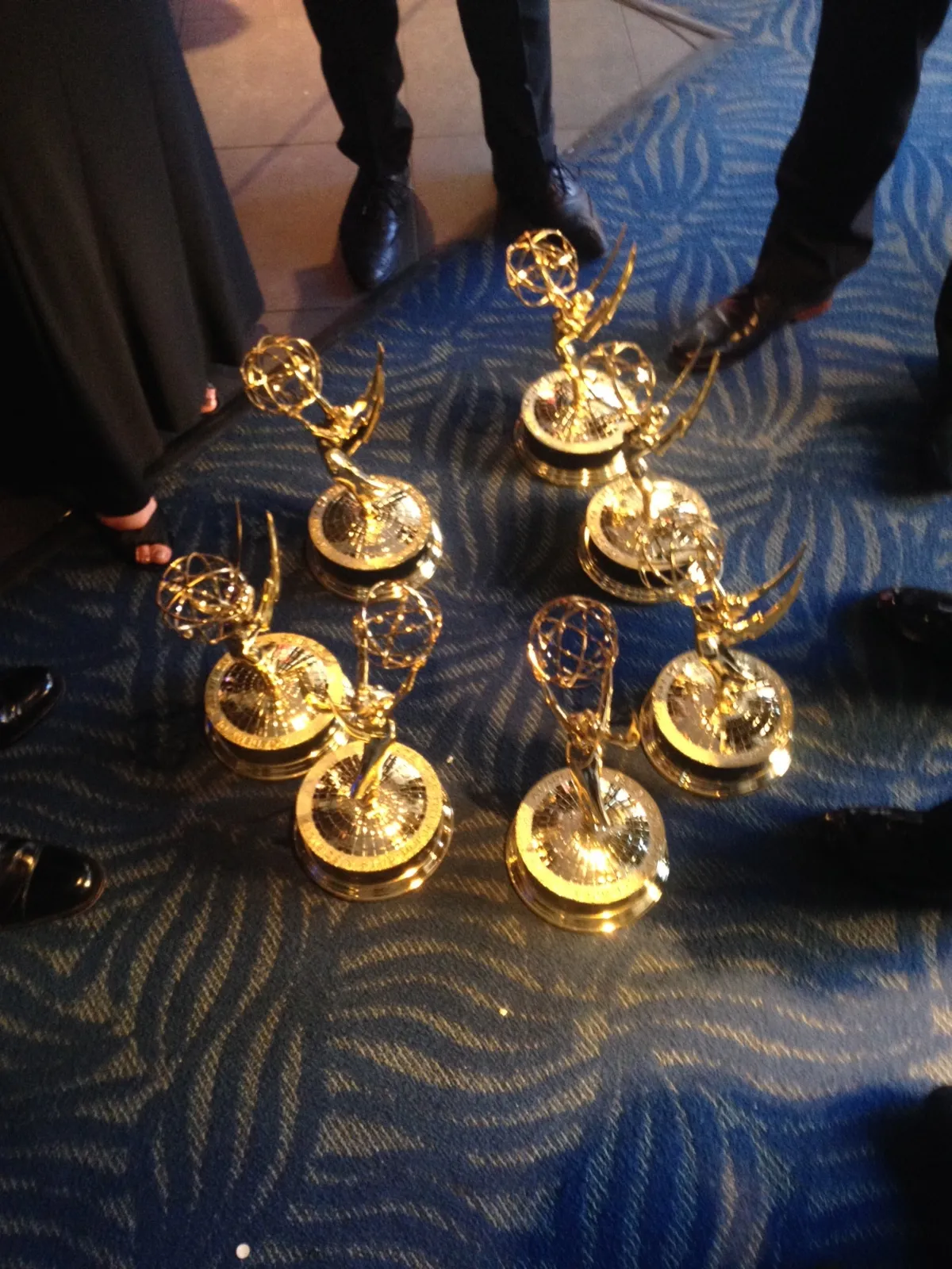 A group of Emmy Awards sitting on the floor while people chat