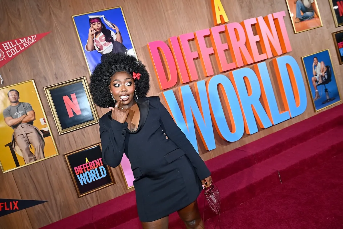 Alijah Kai poses for a photo in a little black dress in front of 'A Different World' sign