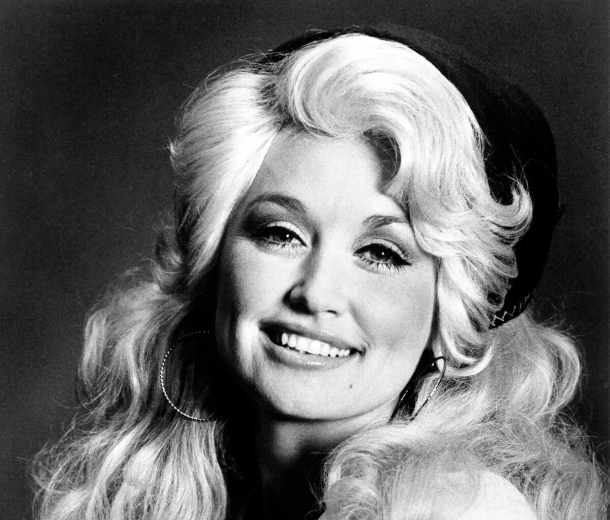 A black and white picture of Dolly Parton with a bandana in her hair.