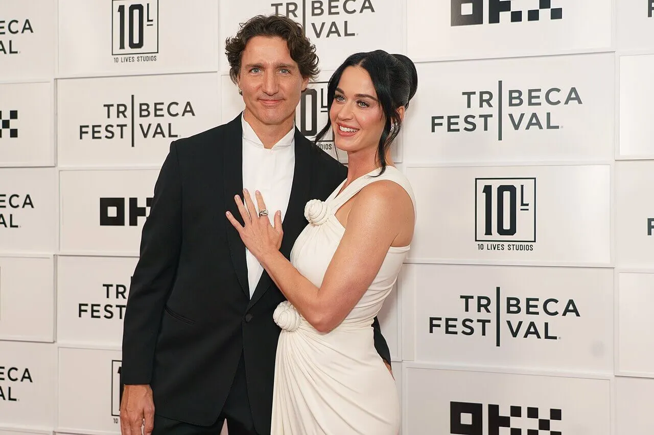 Justin Trudeau wears a suit and stands next to Katy Perry, who wears a white dress.