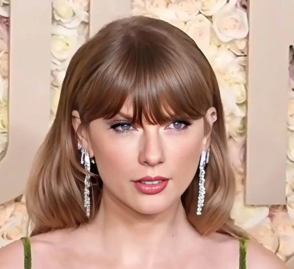 Taylor Swift wears a green dress and diamond earrings.