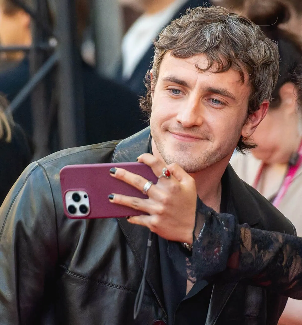 Paul Mescal wears a black jacket and poses for a selfie.