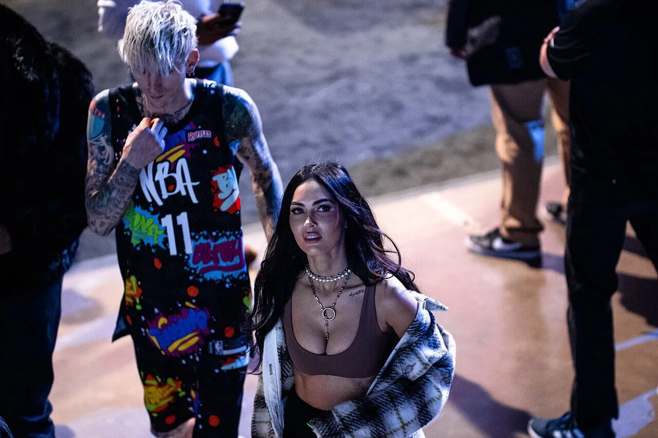 Machine Gun Kelly walks behind Megan Fox.