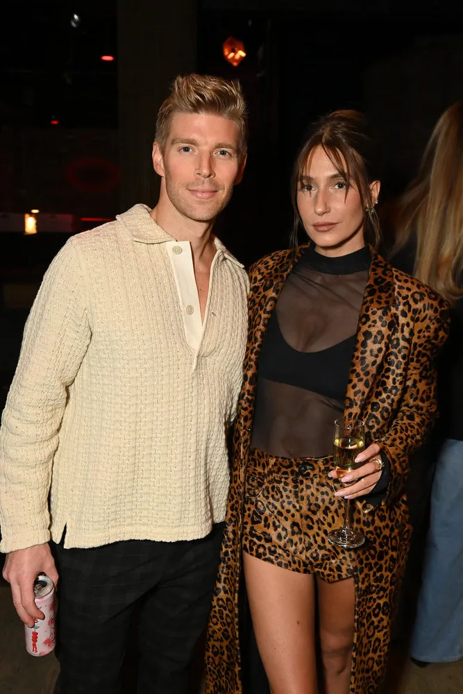 Kyle Cooke wears a sweater and stands with Amanda Batula, who wears a sheer top and leopard print set.