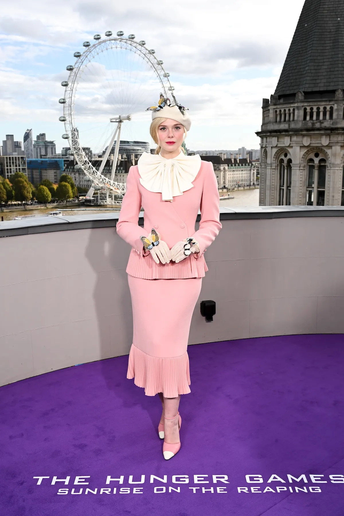 Elle Fanning in a pink skirt suit with a white beret